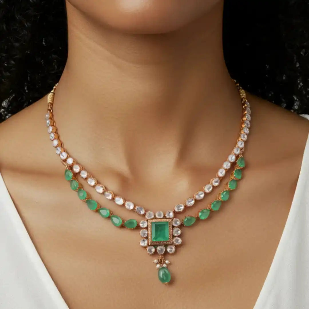 Elegant emerald and diamond necklace with rose gold chain, featuring a square emerald pendant and teardrop accent.