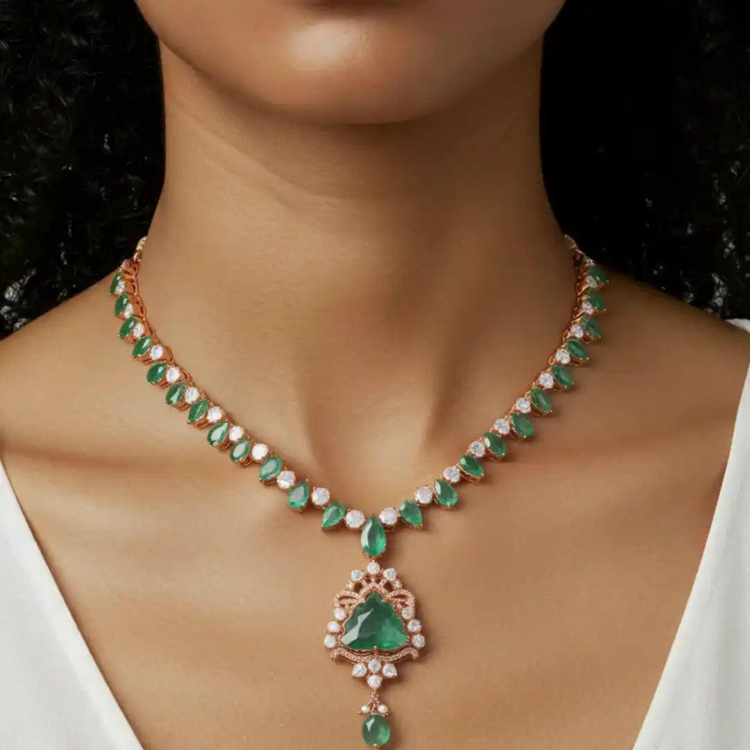 Elegant emerald and diamond necklace with rose gold setting, featuring a teardrop pendant and intricate detailing.