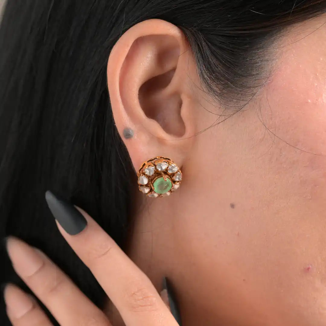 Elegant floral stud earring with green gemstone and clear stones, worn on ear