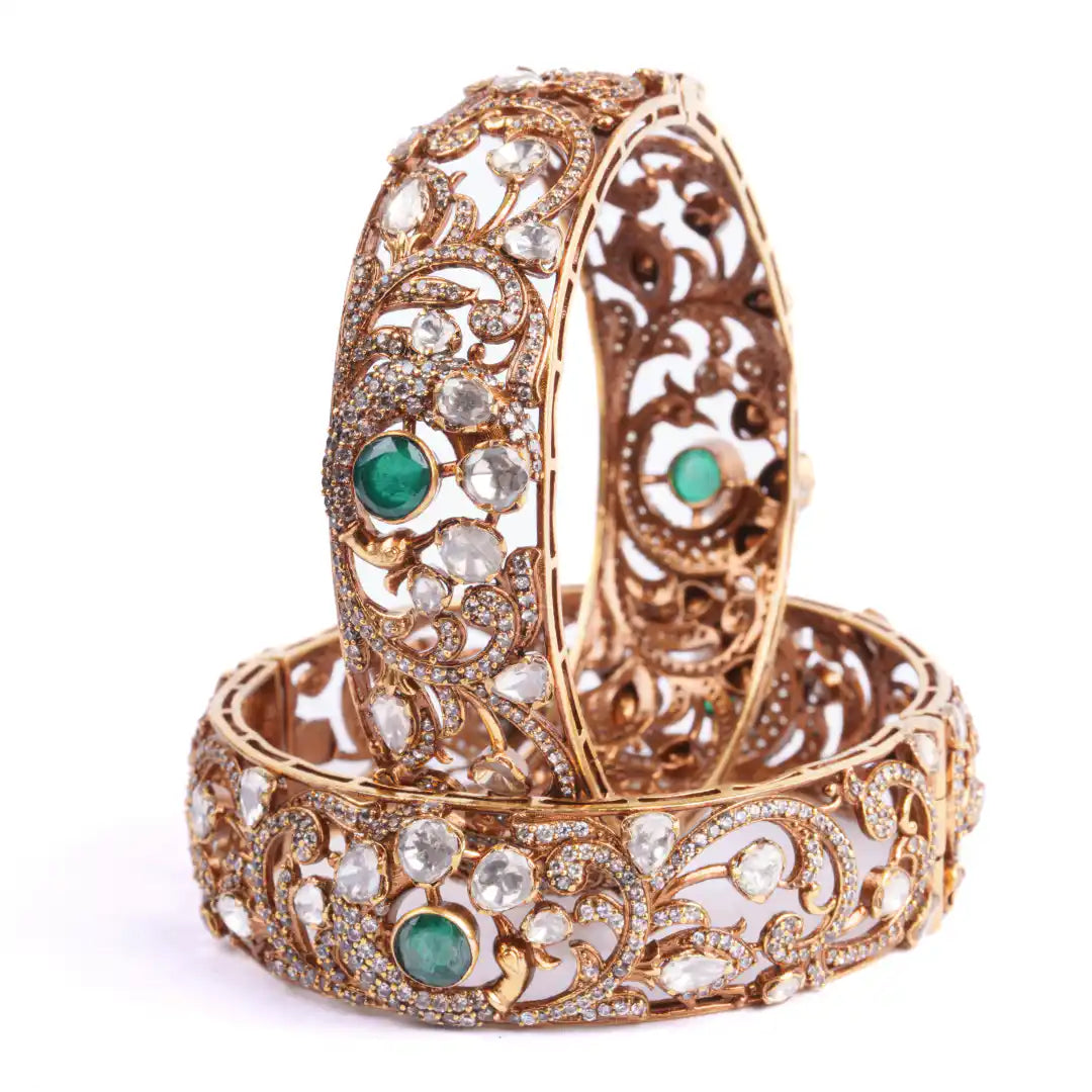 Elegant gold bangles with emerald and diamond accents, intricate filigree design