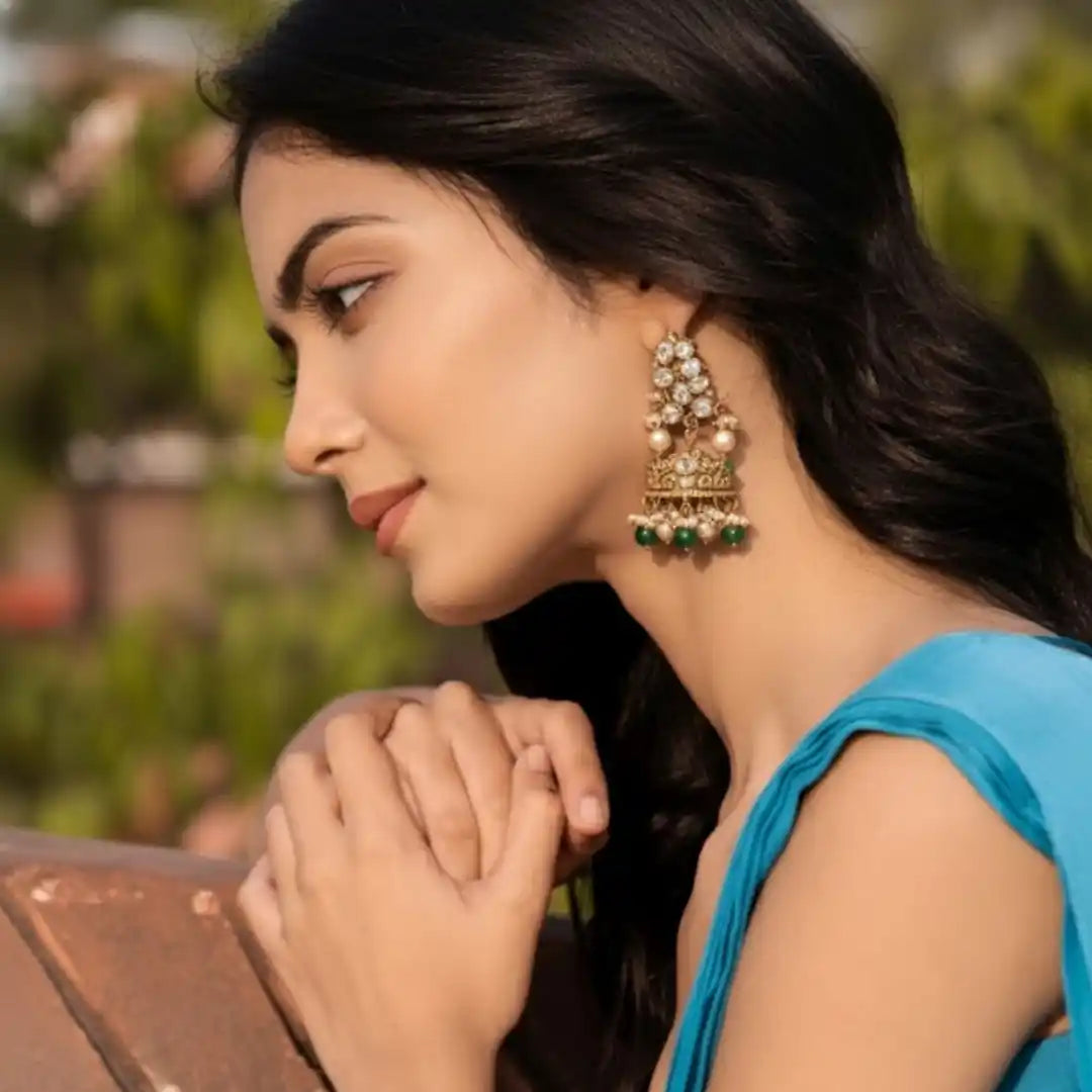 Elegant silver jhumka earrings with green beads and pearls, worn by woman in blue attire
