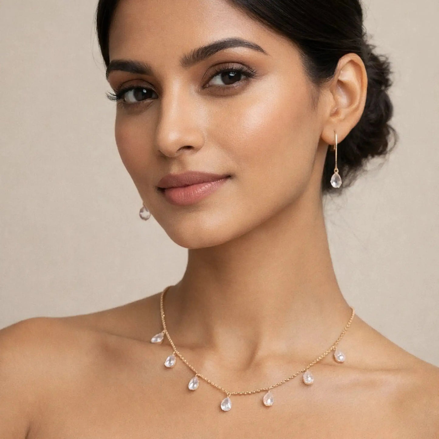 Elegant gold necklace and drop earrings with clear teardrop stones, perfect for women's fine jewelry collections.