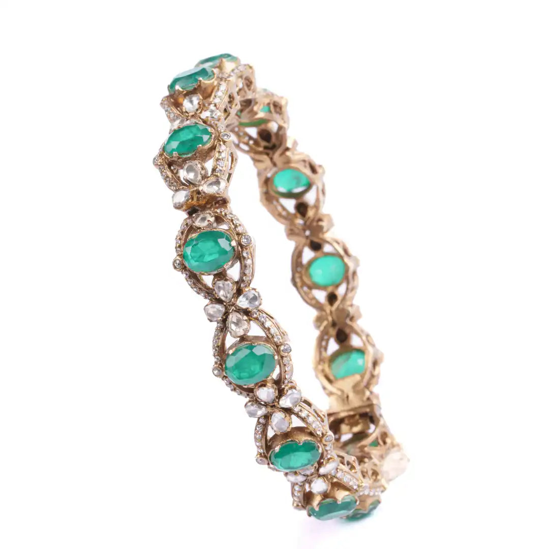 Elegant gold bangle with emerald and diamond accents, perfect for traditional or festive wear.