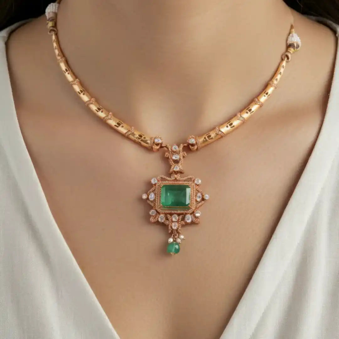 Elegant emerald pendant necklace with rose gold chain and diamond accents, worn by woman in white top