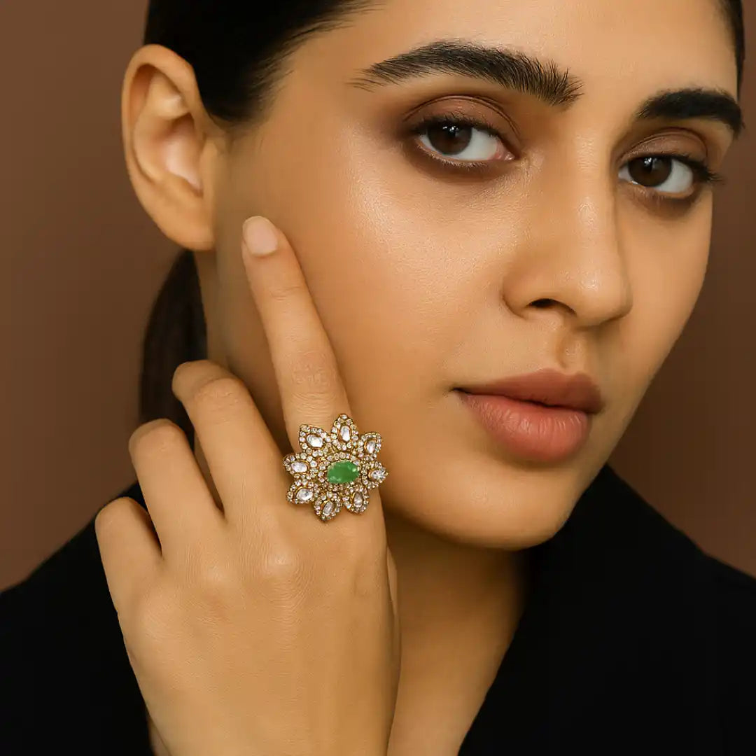 Elegant floral ring with green gemstone and diamond accents, worn on woman's hand near face