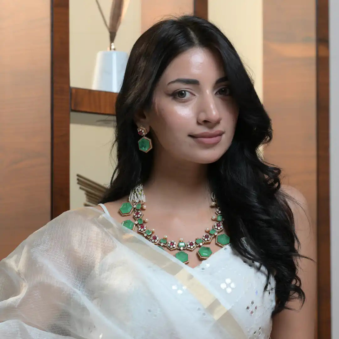 Woman wearing emerald and ruby silver necklace with matching earrings, elegant traditional jewelry set
