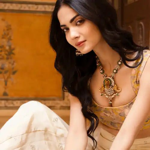 Elegant woman wearing ornate silver necklace and earrings, traditional Indian attire, warm golden backdrop
