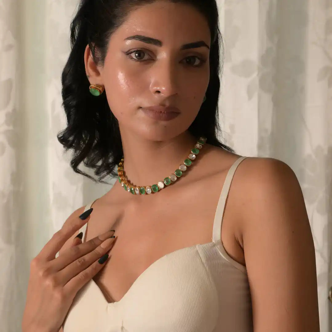 Woman wearing elegant green and white gemstone necklace and matching earrings, silver jewelry set