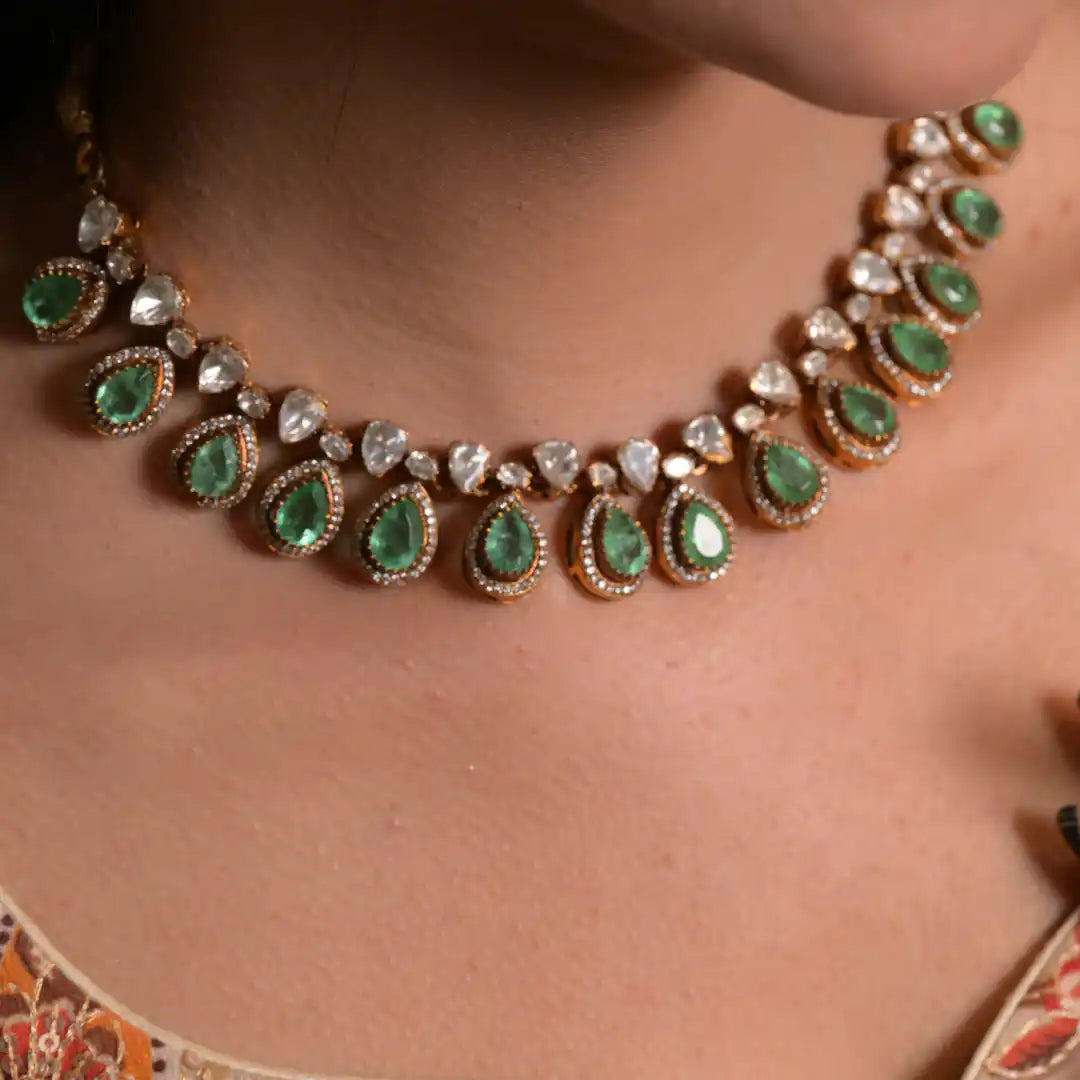 Elegant emerald and diamond necklace with gold detailing, worn on neck for traditional or festive occasions.