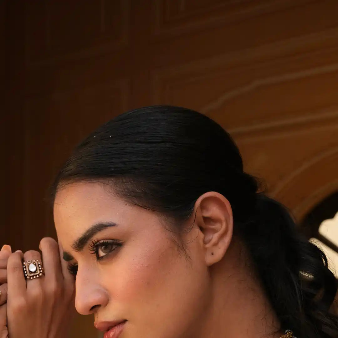 Elegant woman wearing ornate silver ring with pearl, showcasing traditional jewelry design