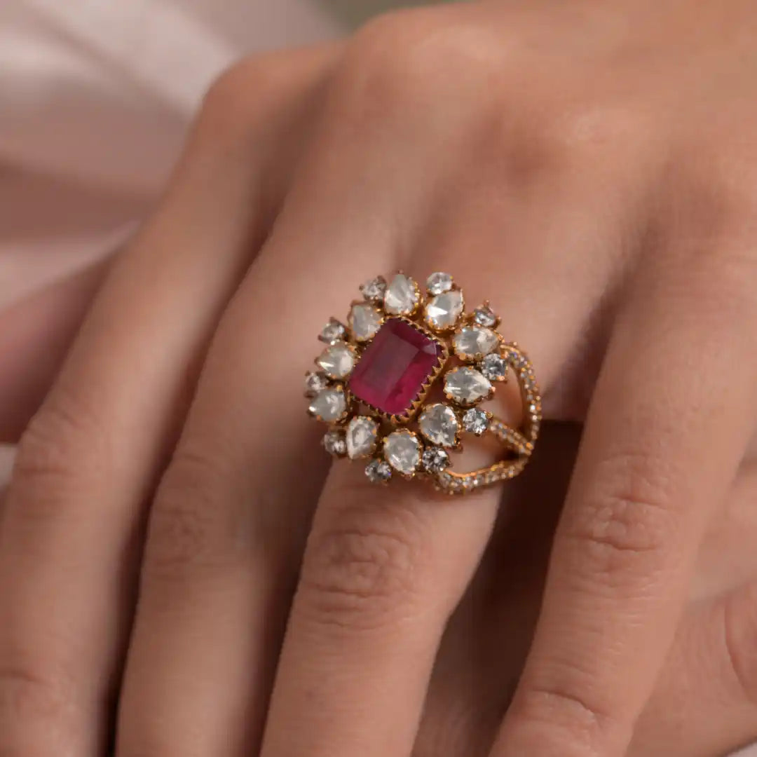 Elegant gold ring with central ruby and diamond accents, worn on finger