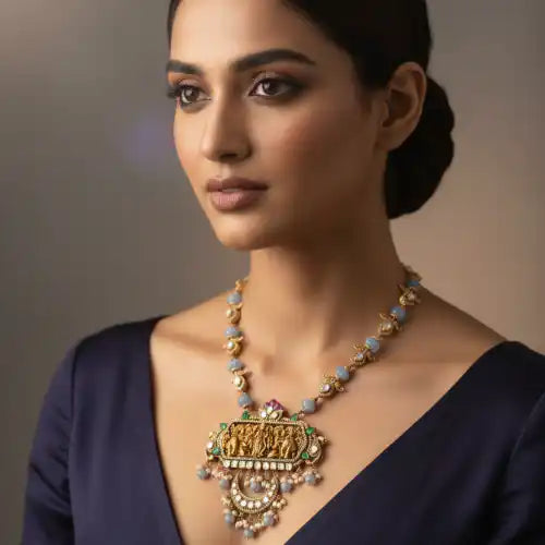 Elegant silver necklace with intricate Ganesha-inspired design, adorned with gemstones and pearls, worn by a woman in a navy blue dress.