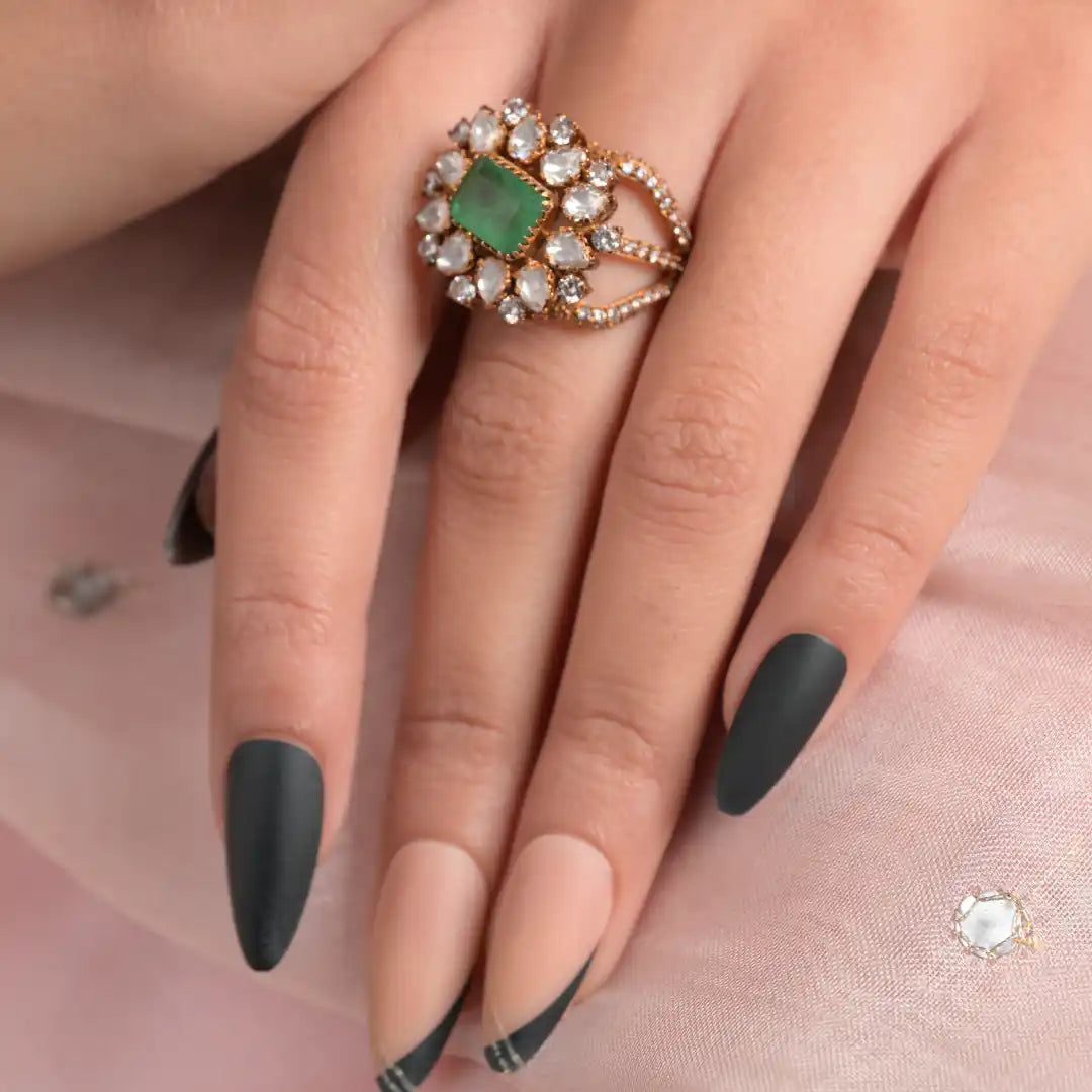 Elegant silver ring with green gemstone and diamond accents, worn on a hand with matte black nails.
