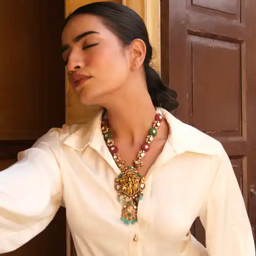 Elegant woman wearing ornate silver necklace with Ganesha pendant and gemstones, styled with white blouse.