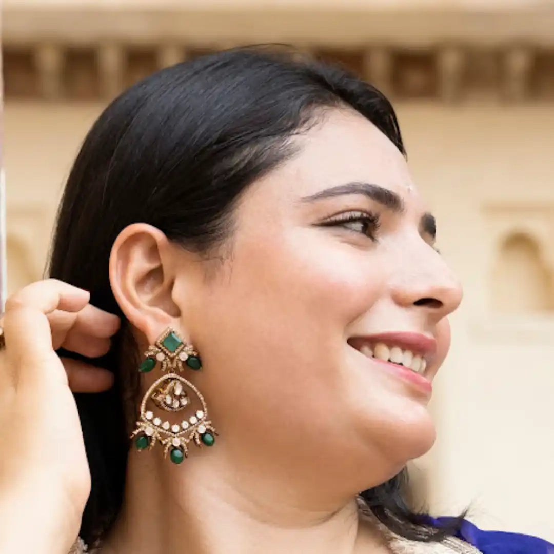 Elegant green stone earrings with intricate gold detailing, worn by smiling woman in traditional attire