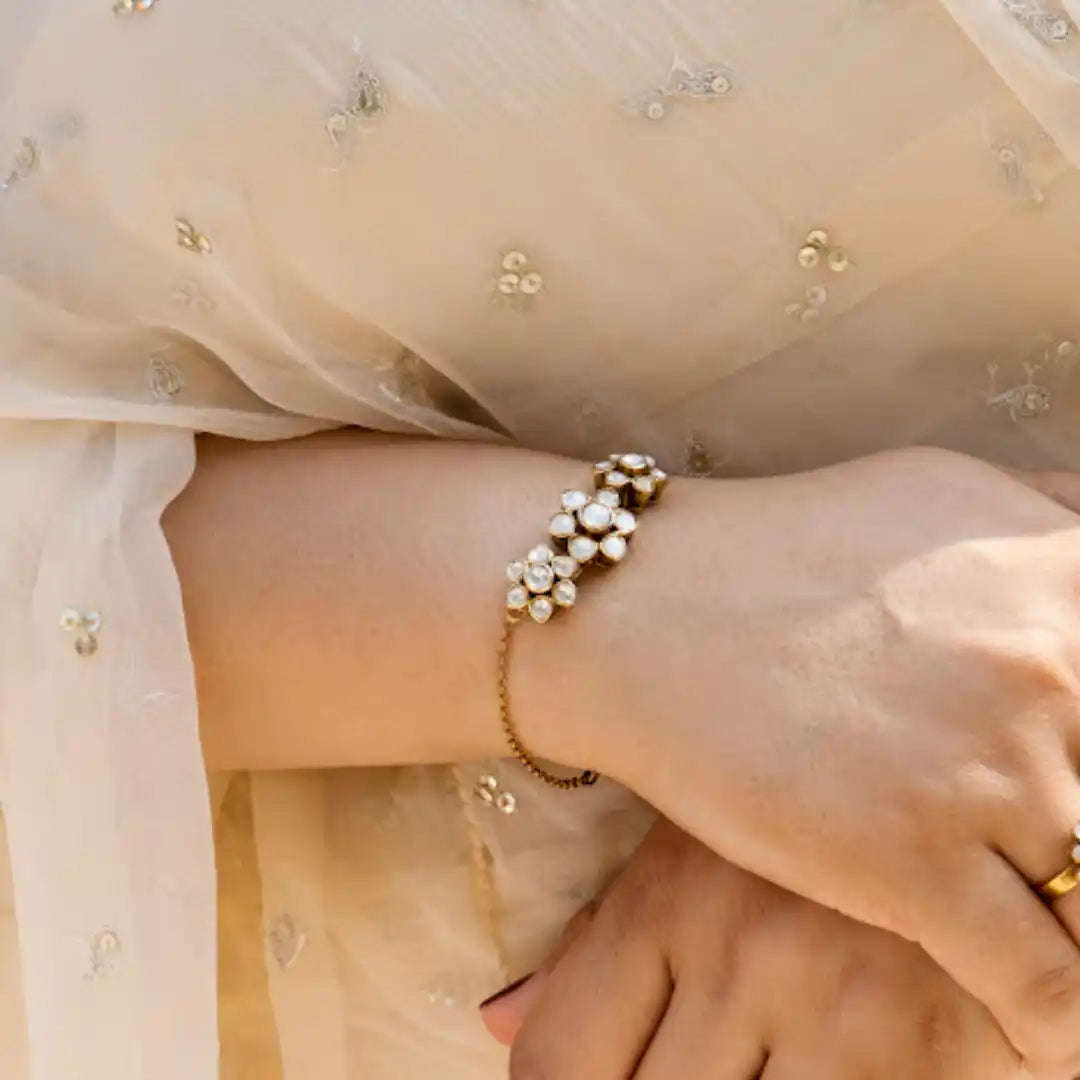 Elegant floral pearl bracelet on wrist, paired with delicate embroidered attire for traditional occasions