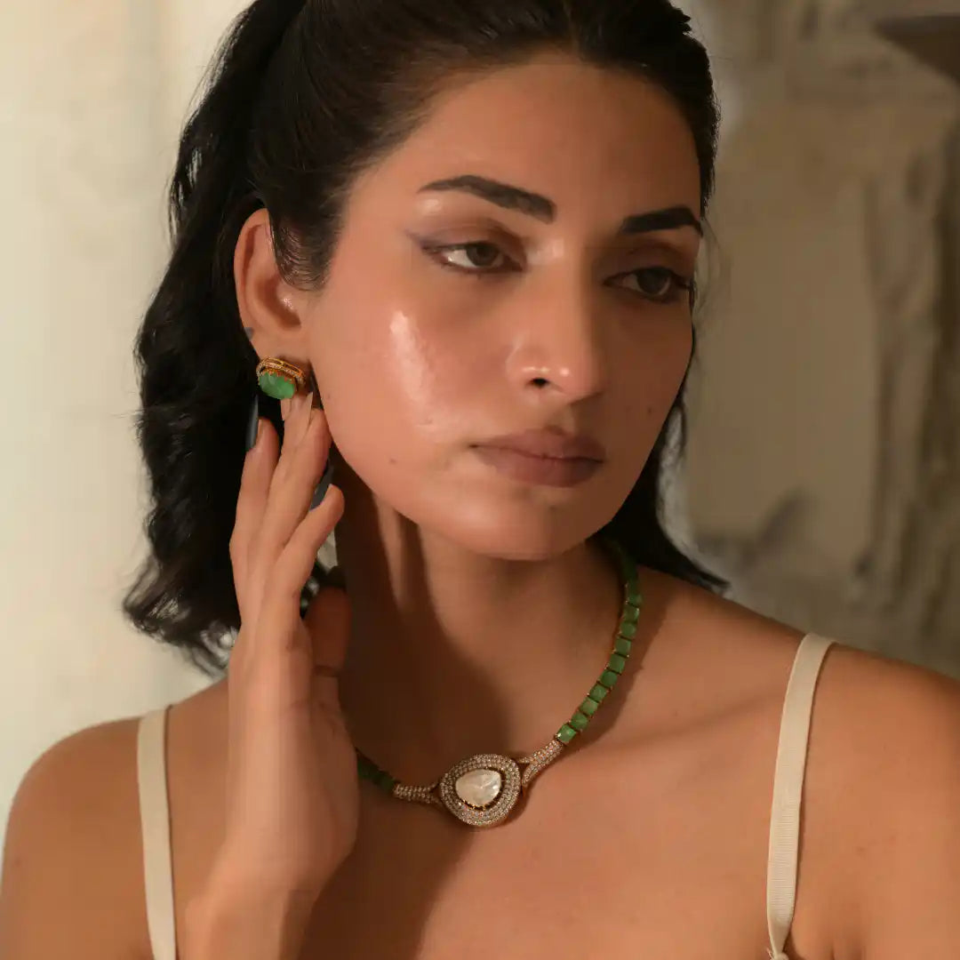Elegant woman wearing green gemstone necklace and matching earrings, showcasing silver jewelry with intricate design.