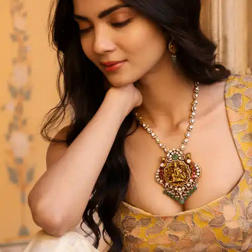 Elegant woman wearing ornate silver pendant necklace with gemstone accents, styled in traditional attire.