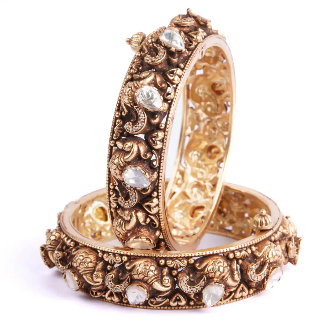 Intricate gold bangles with elephant motifs and clear gemstones, elegant traditional jewelry design