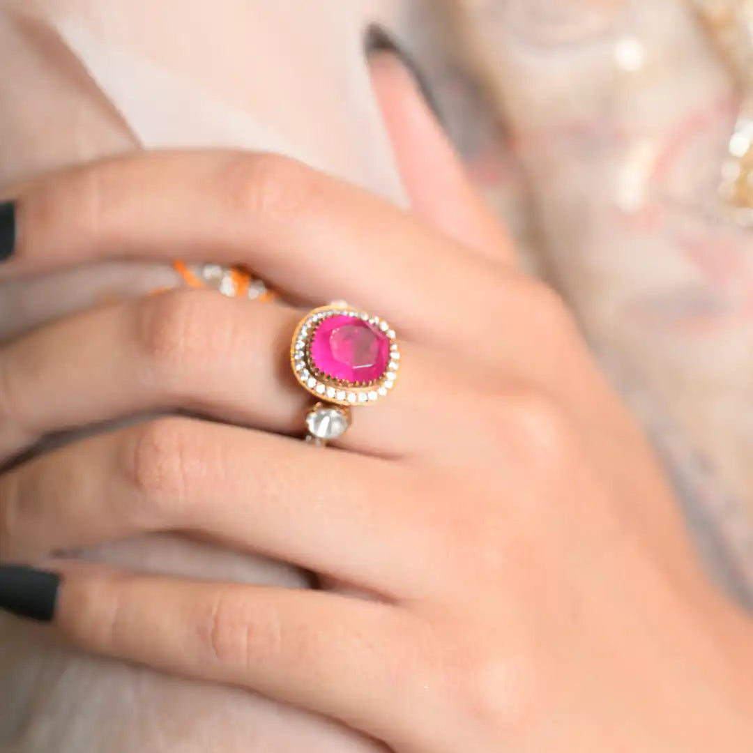 Elegant pink gemstone ring with diamond halo, worn on hand with black nail polish
