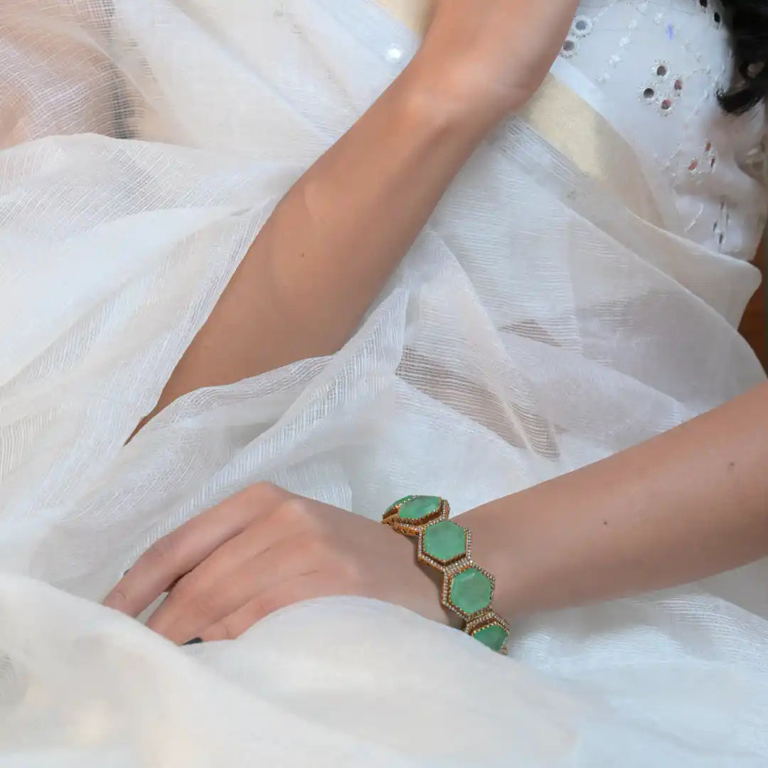 Elegant green stone hexagon bracelet on wrist, worn with white sheer fabric, silver jewelry detail