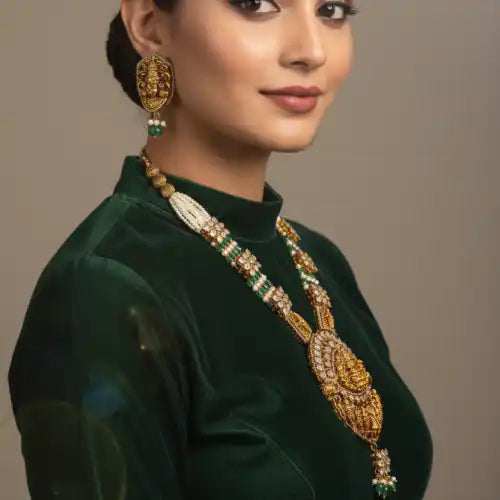 Elegant woman wearing ornate gold and emerald necklace and earrings, styled with green velvet top.