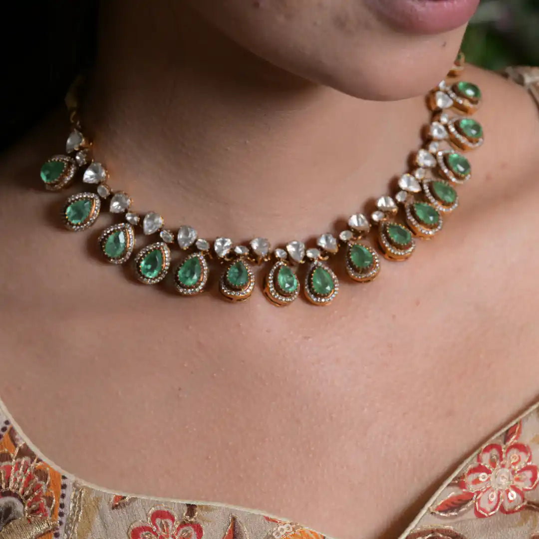 Elegant emerald and diamond necklace with gold detailing, worn with floral attire