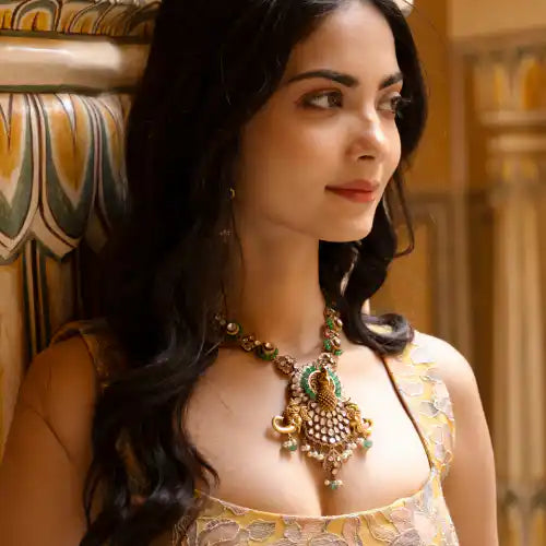 Elegant woman wearing ornate silver necklace with green gemstones, inspired by Ganesha's wisdom and grace.