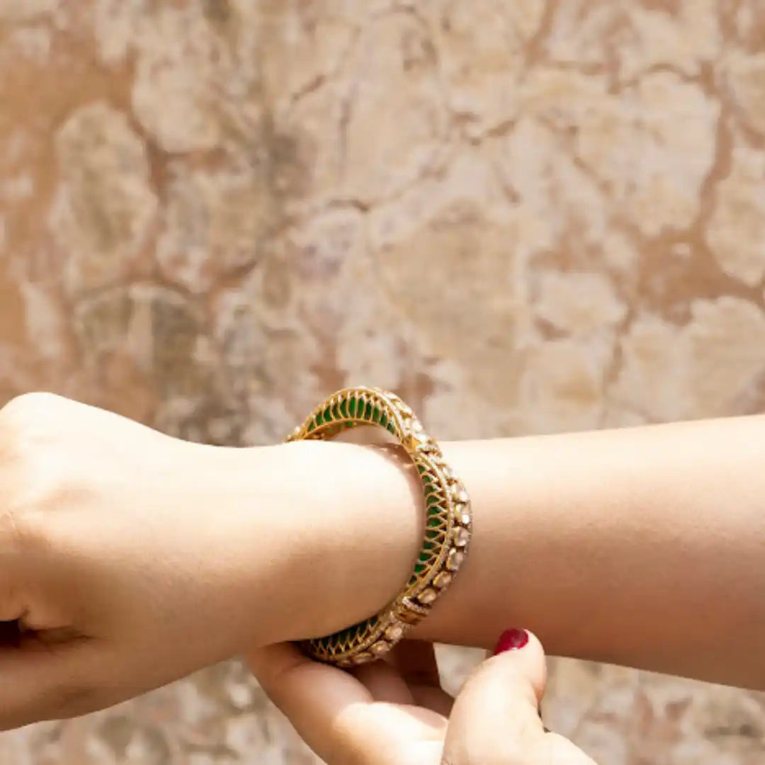 Elegant gold bangle with green enamel and stone detailing on wrist