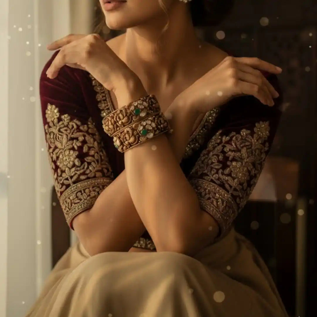 Elegant woman in maroon embroidered outfit wearing ornate silver bangles with green stones