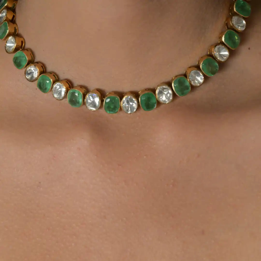 Elegant gold necklace with alternating green and clear gemstones, perfect for festive occasions.