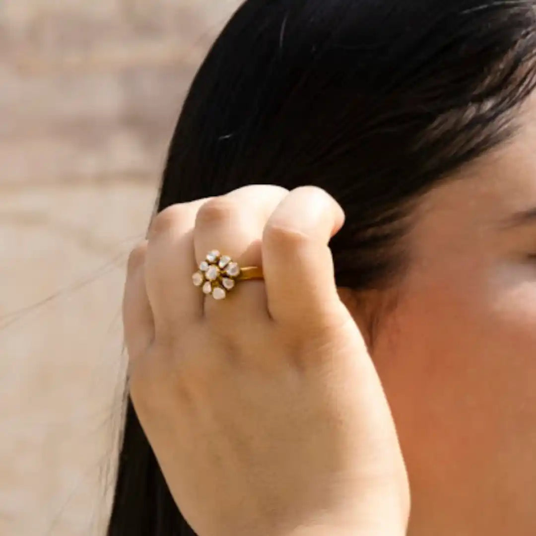 Gold ring with floral gemstone design worn on finger, elegant women's jewelry