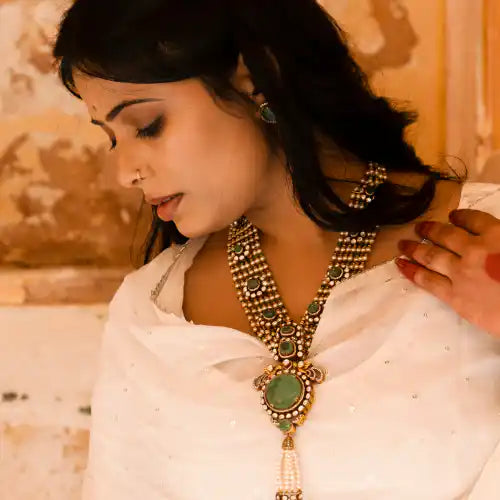 Elegant woman wearing traditional Indian necklace with green gemstones and gold detailing