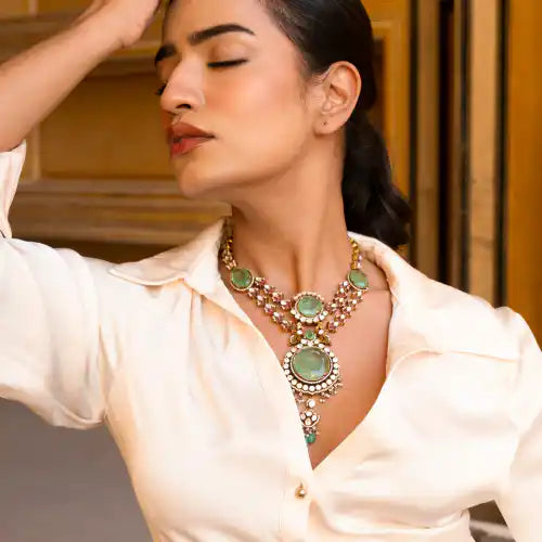 Elegant woman wearing ornate silver necklace with green gemstones, styled for traditional or festive occasions.