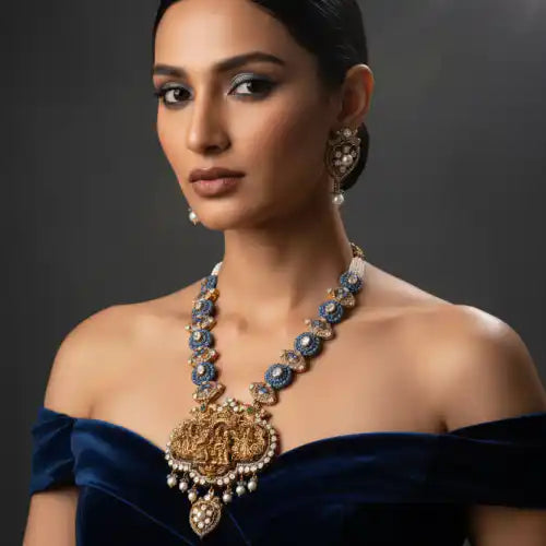 Elegant silver necklace with blue gemstones and pearl accents, paired with matching earrings, worn by a woman in a navy velvet top.