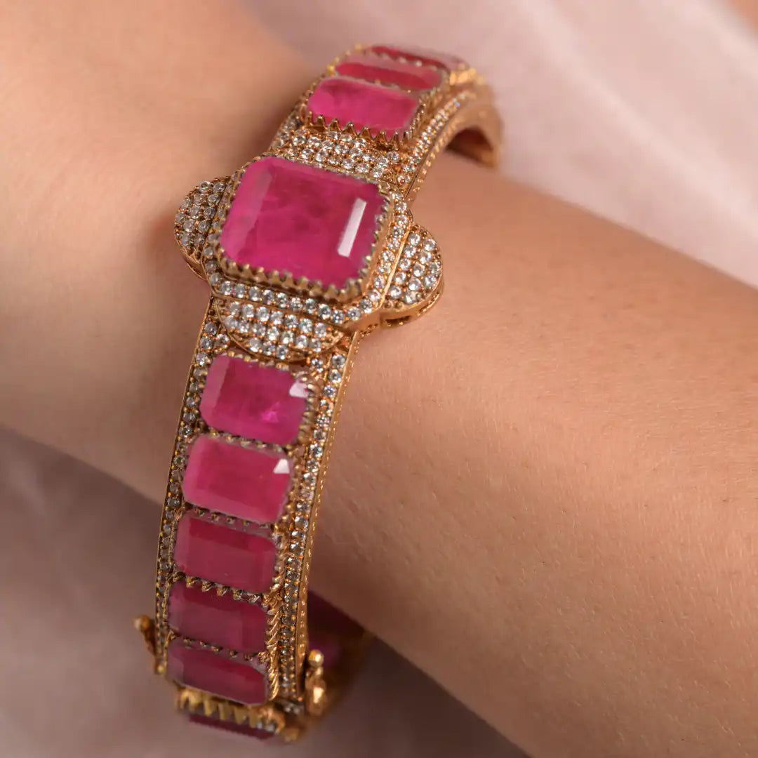 Luxury gold bangle with vibrant pink gemstones and diamond accents, elegant wrist jewelry