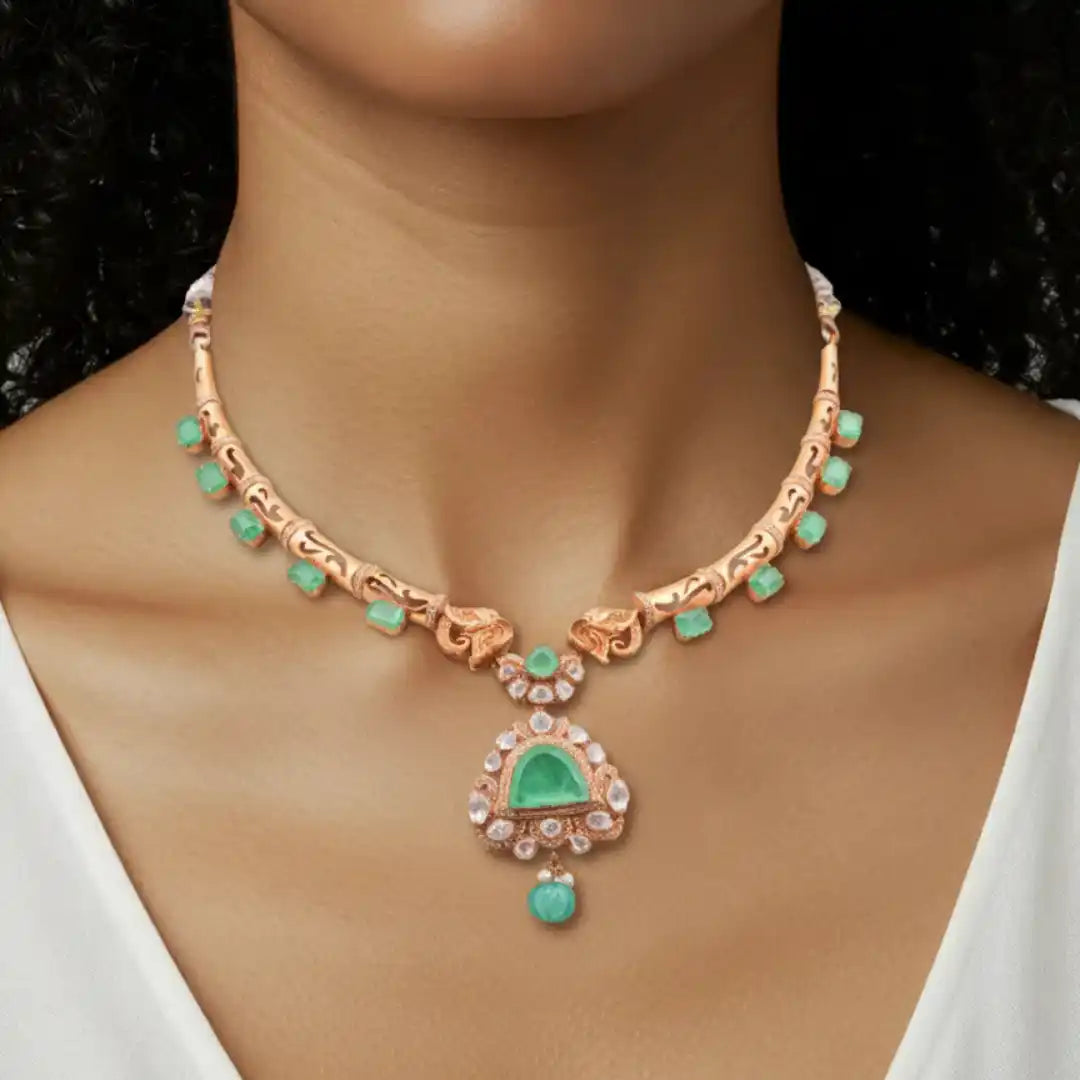 Elegant rose gold necklace with emerald pendant and diamond accents, showcasing intricate craftsmanship.