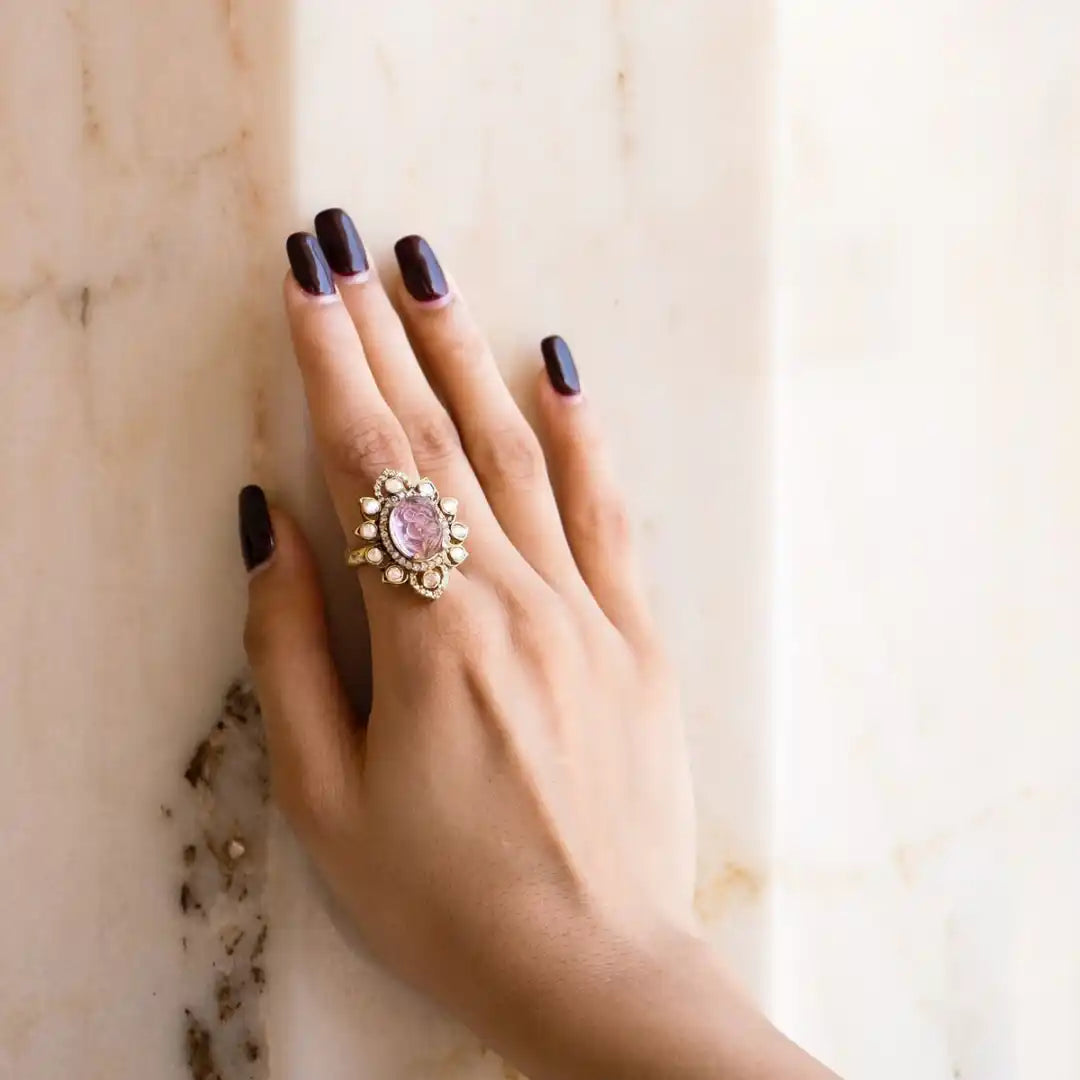 Elegant silver ring with pink gemstone and pearl accents, worn on hand with dark nail polish